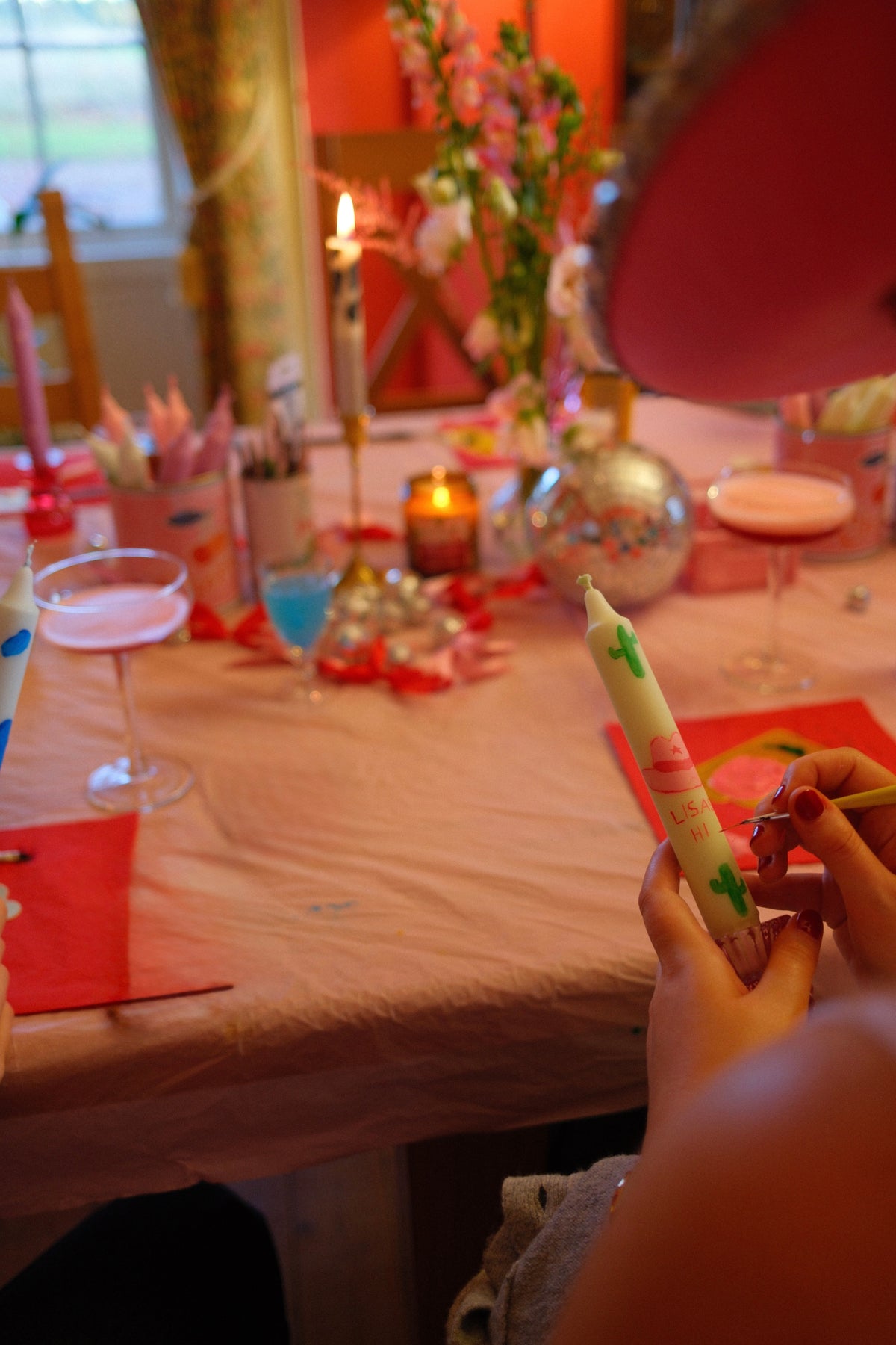 Person holding a decorated candle at a festive table with candles and decorations.