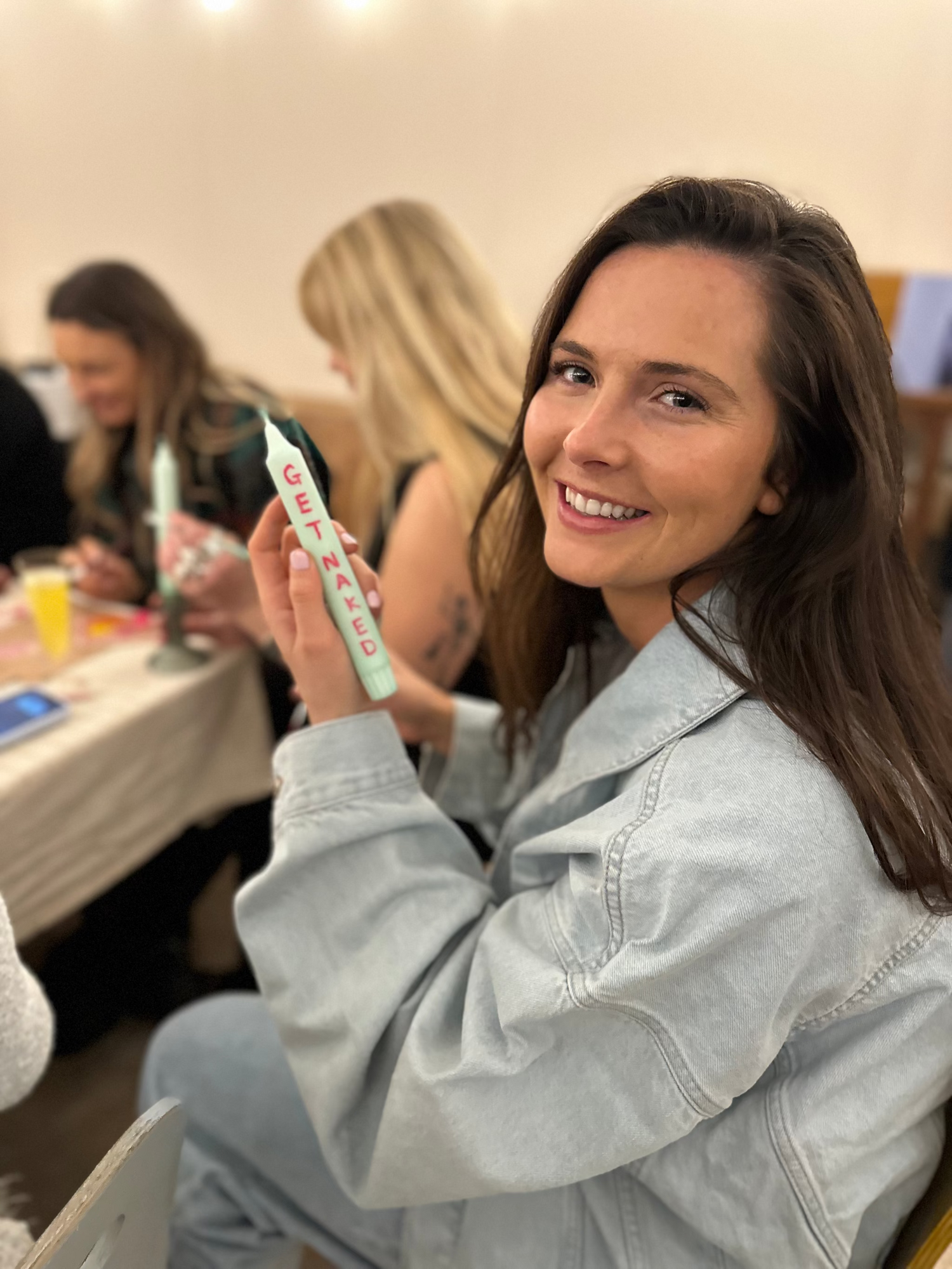 a woman holding up a candle with Get Naked writen on it.